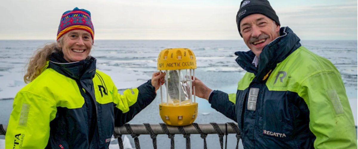 ELIZABETH MCLANAHAN, VICE CHAIR OF PAME AND DIRECTOR AT NOAA, AND OLE ARVE MISUND, DIRECTOR OF THE NORWEGIAN POLAR INSTITUTE (2017-2023) STAND WITH THE PLASTIC IN A BOTTLE CAPSULE ABOARD THE RV KRONPRINS HAAKON. © JESSICA COOK / ARCTIC COUNCIL SECRETARIAT